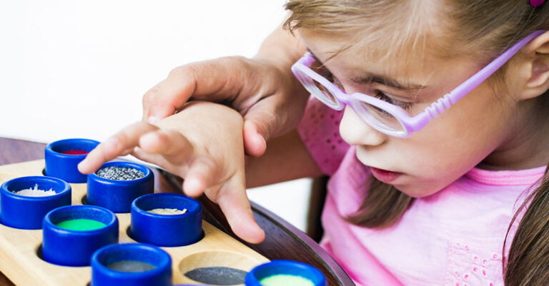 A girl with purple glasses and sensory toys