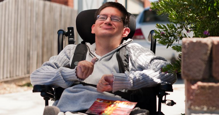Young man who uses a wheelchair outside his house