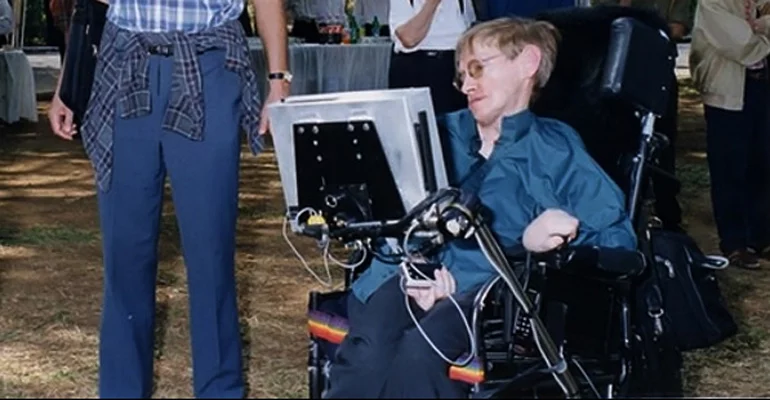 Stephen Hawking outside with his wheelchair and assistive device