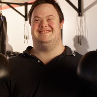 A man with down syndrome wearing boxing gloves