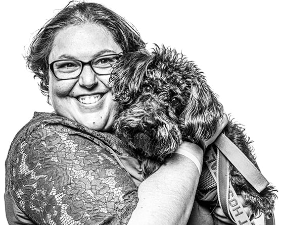 An Aruma customer with a disability cuddling a black dog
